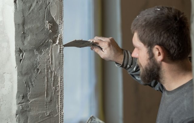 a-man-plasterer-mounts-a-perforated-painting